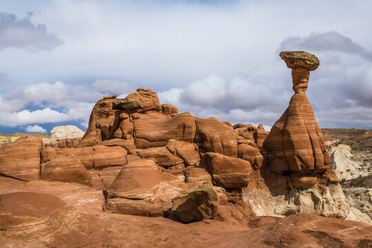 View of vibrant, red rock formations and toadstool hoodoos punctuate the stark landscape under a dramatic sky, a testament to nature's artistry, Kanab, Utah, Iceland.
