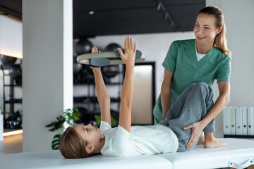 Young patient practicing movement using Pilates ring under supervision