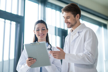 Obraz premium Two doctors talking in the clinics corridor and looking contended