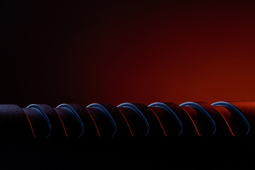 A spiral object rests on a flat surface under soft lighting. The background shows warm colors, creating a contrast with the dark tones of the spiral design.