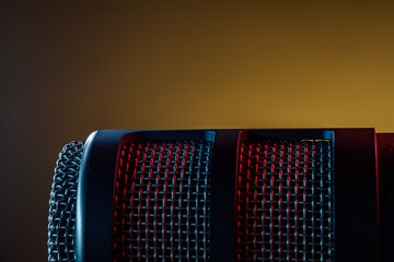 A microphone is positioned in a dimly lit room with a red light reflecting off it. This scene captures the focus on sound recording activity during the evening.