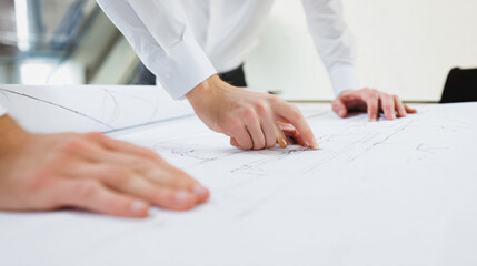Two people reviewing and pointing at architectural blueprints on a table.