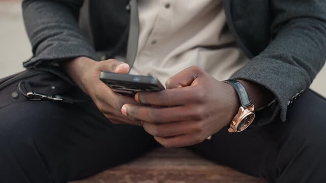 Close view of rough hands with tiny scars holding smartphone while seated outdoors, showing human skin, and natural light reflection symbolizing resilience, communication, and real life authenticity