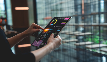 A person interacts with a digital tablet displaying data visuals, set against a modern, glass-walled environment.
