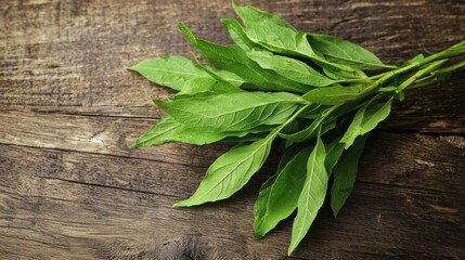 A bunch of fresh green leaves on a wooden table.