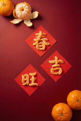Lunar New Year Chinese Characters Chun Ji Wang Made of Mandarin Orange on Red Paper Flat Lay