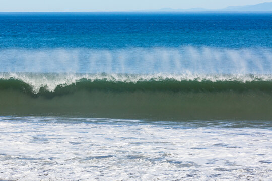 Waves reaching the shore and breaking on the sand.