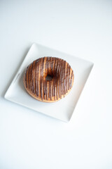 Sweet glazed donut with chocolate drizzle on white plate, minimalist style, bakery shop, dessert cafe ads
