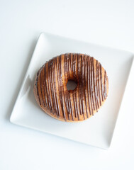 Tasty donut with dark chocolate icing on square plate, top view lighting, pastry shop, confectionery ads