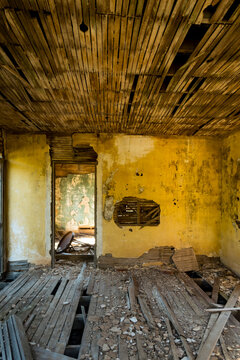 A shell of a building, a derelict house interior, exposed timbers and peeling paintwork, foreclosure, economic ruin.