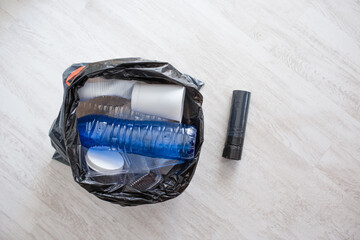 Sorting plastic waste into black garbage bag in neutral light, recycling business or eco campaign with mockup