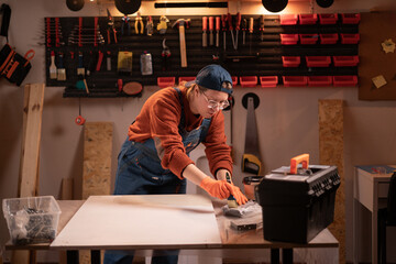 Craftswoman and DIY handmade. carpenter woman applies paint on furniture parts using paintbrush in...