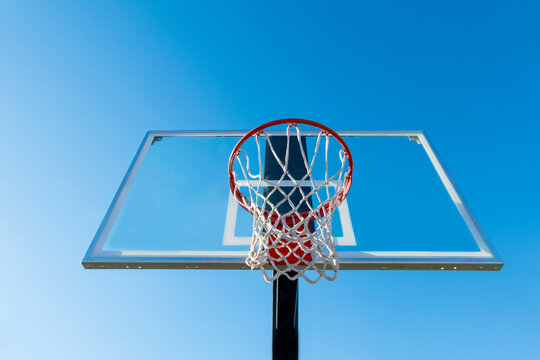 Basketball hoop and backboard, low angle view, against a blue sky.