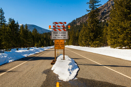 Road closed sign in mountains, North Cascades Highway, winter time, snow drifts.