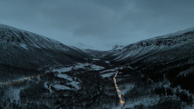 Beautiful drone photography of the Norwagian landscape during a lovely spring evening, following an enlighted pathway that serves as a stroll for locals, near Tromsdalen