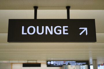 Airport lounge directional sign with white text on black background pointing to the right in travel terminal