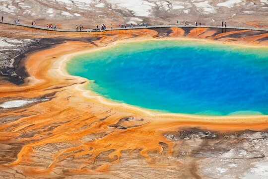 Colorful Grand Prismatic Spring in Yellowstone's Midway Geyser Basin with vivid rainbow hues and tourists on the boardwalk.