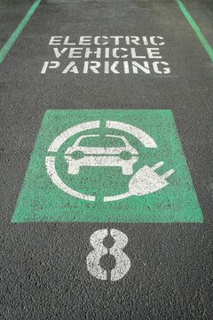 Marked parking space reserved for electric vehicles with green EV symbol and charging plug icon, Portland, Oregon.