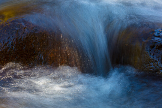 Long exposure of river water flowing over rocks, impressionistic effect.