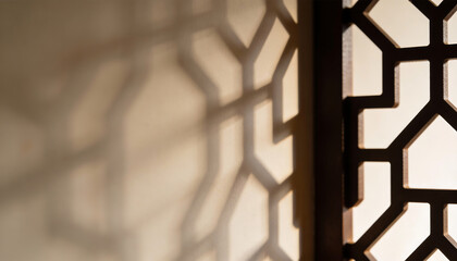 Geometric screen panel casting patterned shadows on neutral wall warm light minimalist islamic inspired architecture background with shallow depth of field