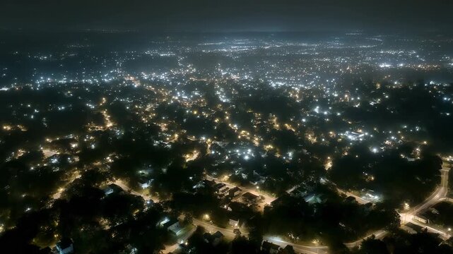 A nighttime aerial view of neighborhoods with patchy power restoration, blocks of light and darkness revealing grid recovery in progress. cinematic color correction, natural uneven lighting yet