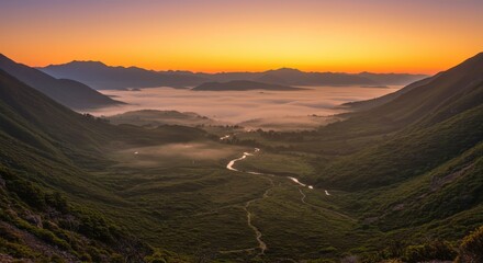 Obraz premium Verdant mountain valley displays winding river beneath a vibrant sunrise fog layer