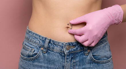 Woman in jeans adjusting her Piercing ring navel piercing