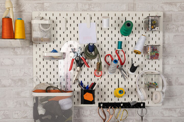 Pegboard wall organizer holding sewing tools and craft supplies
