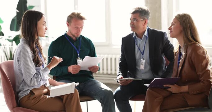 Group of professionals sitting in office during business team discussion, listening as young adult female colleague, presents idea, explain opinion or point. Corporate training, leadership, teamwork