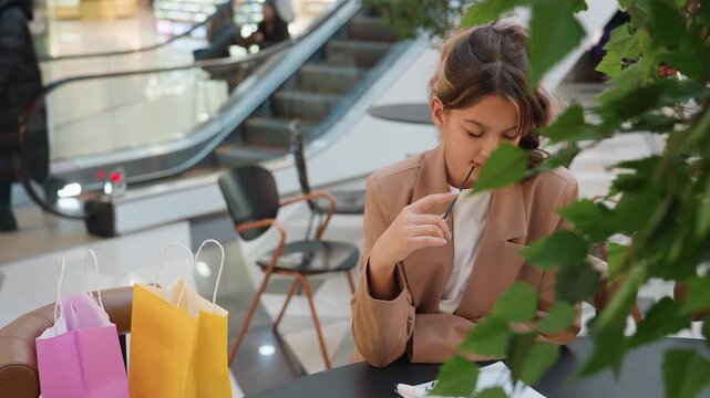 woman samples perfume, woman tests fragrance near shopping bags, relaxed woman indulges in perfume testing at shopping mall, woman enjoys fragrant moment with tester spray and shopping bags nearby