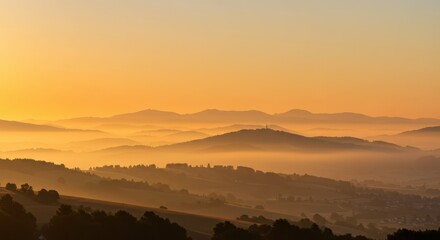 Rolling hills and distant peaks emerge from thick layers of golden morning fog