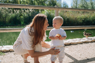 Mother and toddler son enjoying park outing with duck