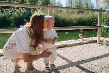 Mother kissing toddler son in park by pond