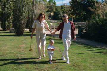 Happy family walking in park holding hands