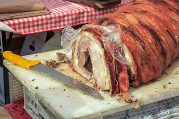 Sliced porchetta roast with crispy skin and juicy meat on a cutting board, ready to serve....
