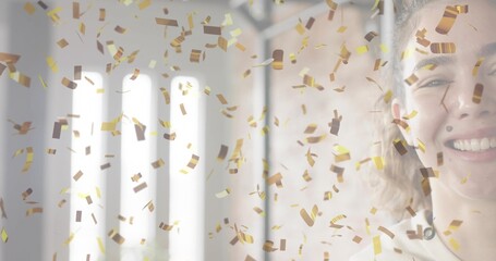 Smiling woman in light top celebrating in studio by tall windows, falling gold confetti, copy space