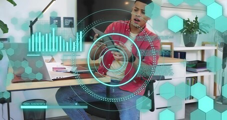 Checking smartphone, man wearing red shirt, jeans at home office desk with laptop and teal HUD