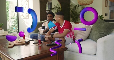 Chatting, two men wearing red jersey and jacket sitting in living room with pizza and soda