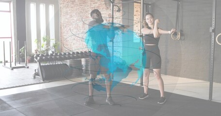Stretching two adults wearing athletic gear in gym, with dumbbell rack and holographic globe