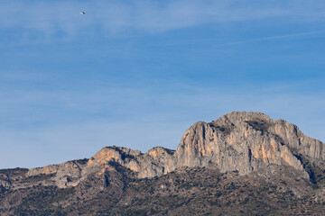 Cadena monta&ntilde;osa del Benicadell bajo cielo azul con nubes brumosas, Beniarres, Espa&ntilde;a