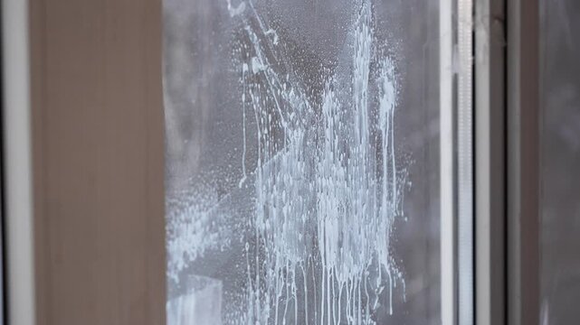 woman cleans dirty window from glue from old scotch tape, sprays window cleaning liquid, soaks glue from scotch tape. cleaning, cleaning, window washing