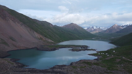 Obraz premium Aerial view of a turquoise mountain lake surrounded by rugged terrain. Clear water contrasting with rocky landscape, photographed from a drone.