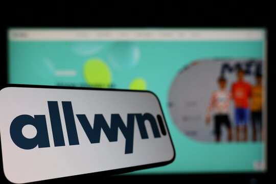 Kiel, Germany - 01-12-2026: Smartphone displaying Allwyn logo in front of the company website on a monitor