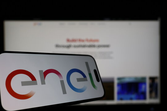 Kiel, Germany - 01-12-2026: Smartphone displaying Enel logo in front of the company website on a monitor