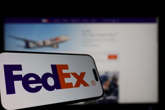 Kiel, Germany - 01-12-2026: Smartphone displaying FedEx logo in front of the company website on a monitor