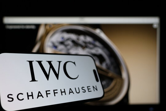 Kiel, Germany - 01-12-2026: Smartphone displaying IWC Schaffhausen logo in front of the company website on a monitor
