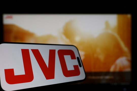 Kiel, Germany - 01-12-2026: Smartphone displaying JVC logo in front of the company website on a monitor
