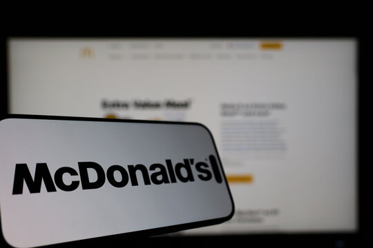 Kiel, Germany - 01-12-2026: Smartphone displaying McDonalds logo in front of the company website on a monitor