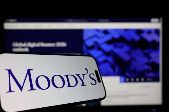 Kiel, Germany - 01-12-2026: Smartphone displaying Moody&acute;s logo in front of the company website on a monitor
