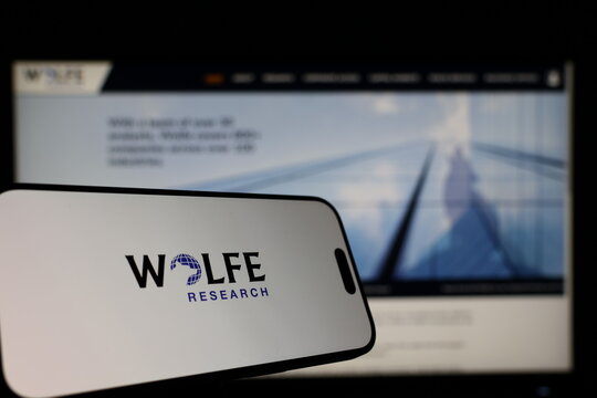 Kiel, Germany - 01-12-2026: Smartphone displaying Wolf Reserch logo in front of the company website on a monitor